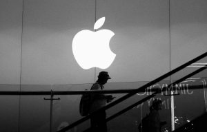 Homem subindo escada com logo da Apple ao fundo