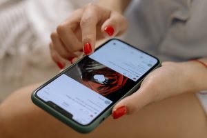 Mulher com unhas vermelhas lê uma postagem em rede social