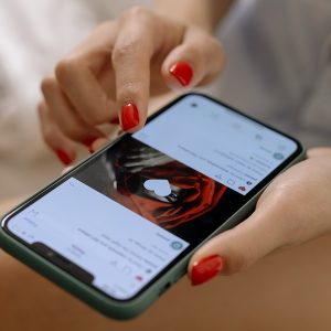 Mulher com unhas vermelhas lê uma postagem em rede social