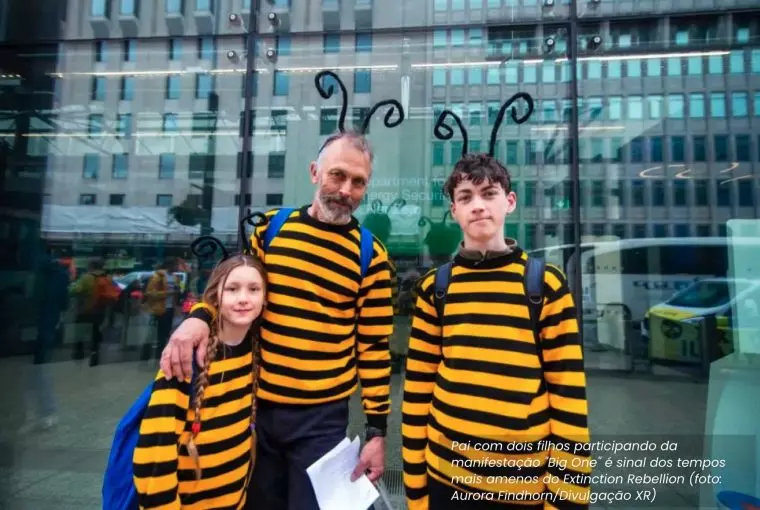 Pai com filhos vestidos de abelha em protesto do grupo de defesa do clima Extinction
