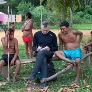 jornalista dom philips sentado em meio à indígenas durante trabalho de jornalismo