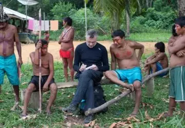 jornalista dom philips sentado em meio à indígenas durante trabalho de jornalismo