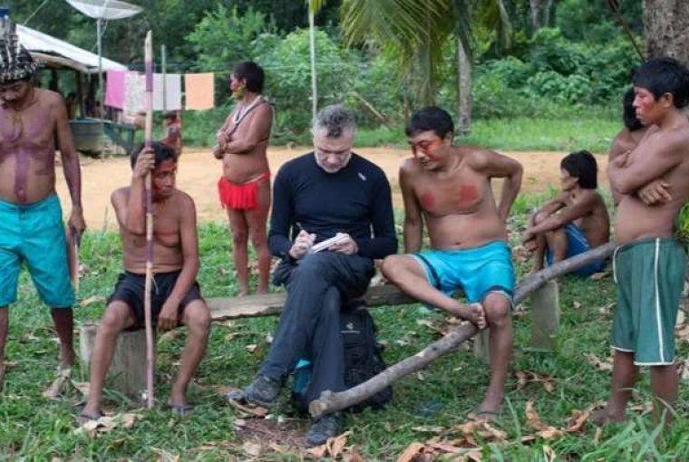 jornalista dom philips sentado em meio à indígenas durante trabalho de jornalismo