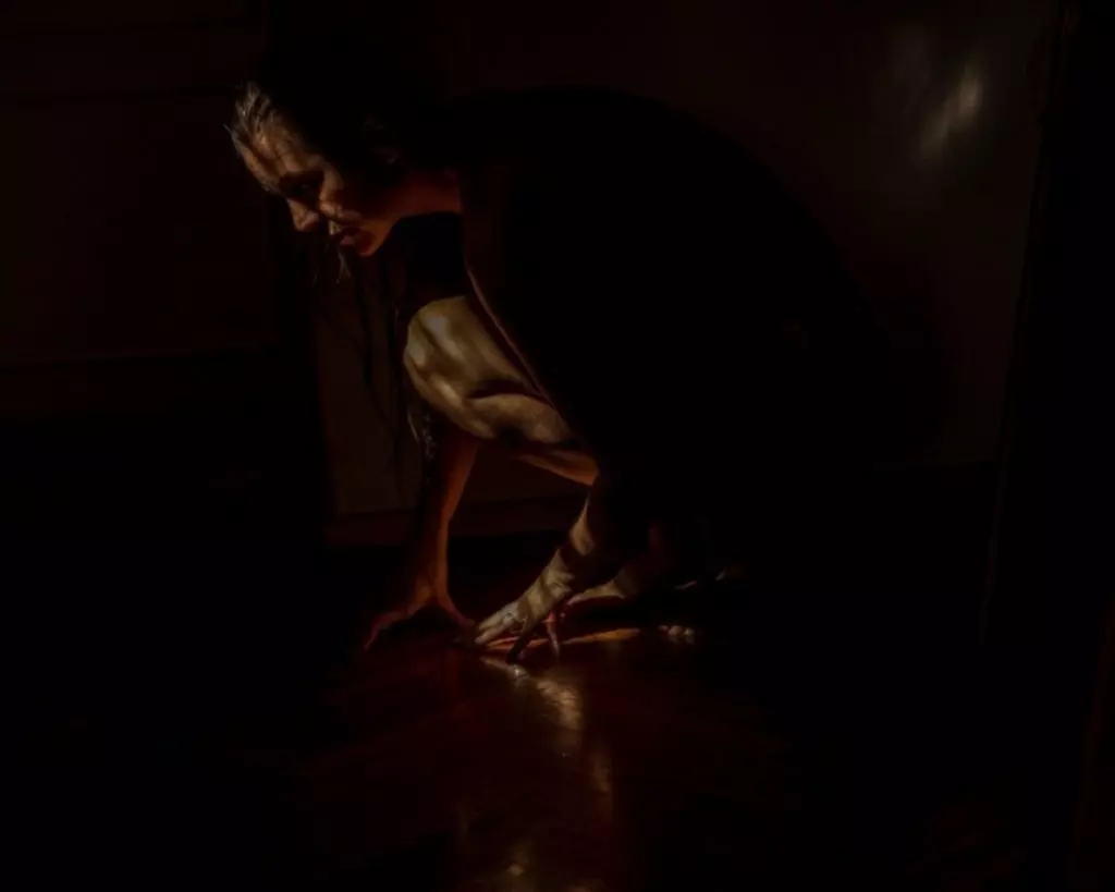 Foto de uma mulher ajoelhada no escuro é uma das premiadas no prêmio de fotografia ética World Report Award Alemanha-Argentina