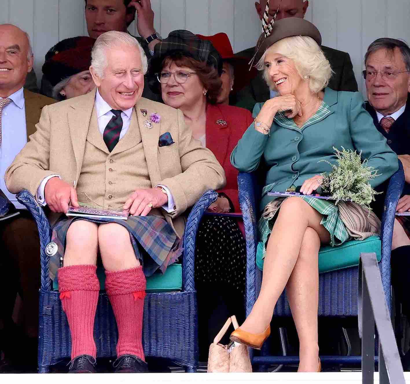 Rei Charles III, vestido em trajes escoceses, e Rainha Camilla riem durante o evento "The Braemar Gathering", na Escócia, em setembro de 2023