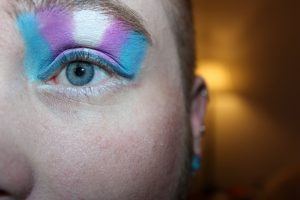 Mulher com olhos pintados azul rosa Jornalista trans LGBTQ+ diversidade inclusão mídia