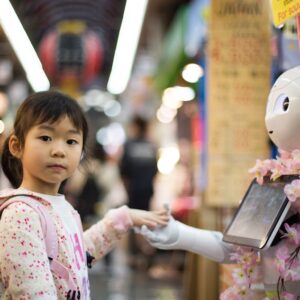Menina cumprimenta robô alimentado por IA, tecnologia que vem sendo cada vez mais usada na educação