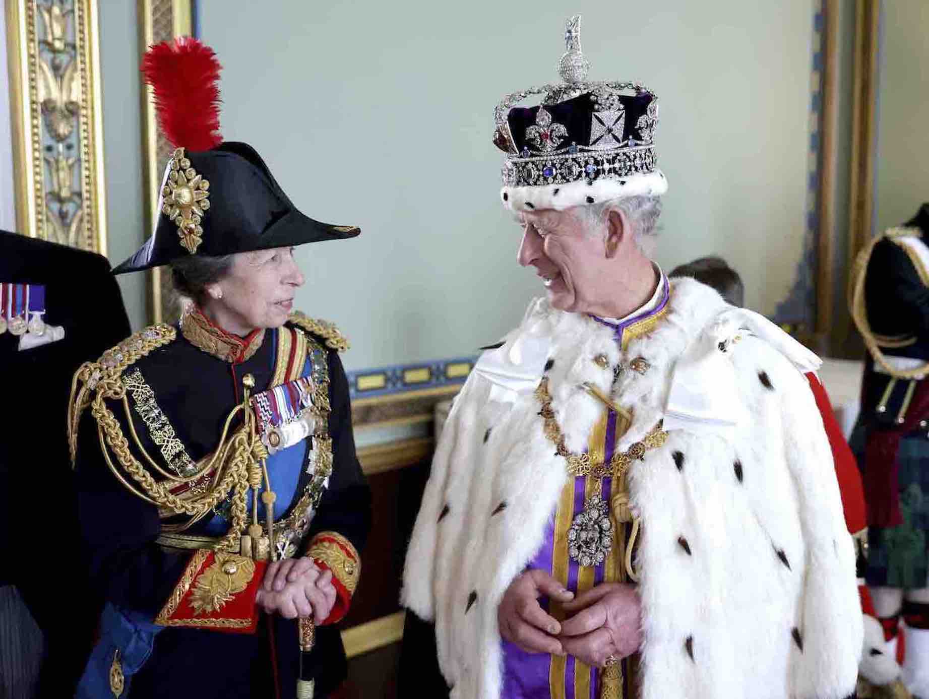Rei Charles III usando a coroa e as insígnias reais ao lado de sua irmã, no dia de sua coroação