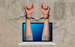 Criminalização jornalismo jornalista liberdade de imprensa computador mão algema