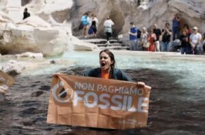 Mulher com faixa contra combustíveis fósseis na Fontana di Trevi, em Roma