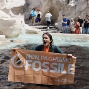 Mulher com faixa contra combustíveis fósseis na Fontana di Trevi, em Roma