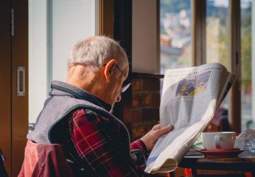 Homem lendo jornal notícias políticas mídia partidária