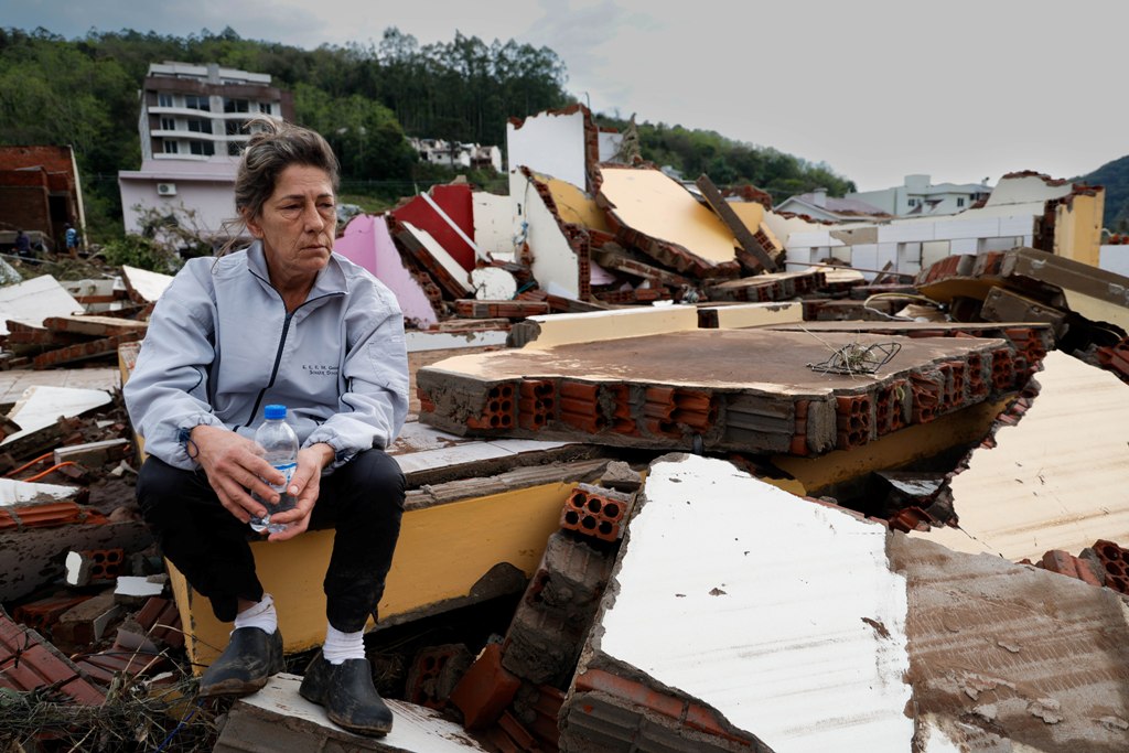 Mulher sentada entre os escombros após ciclone tropical no sul do Brasil