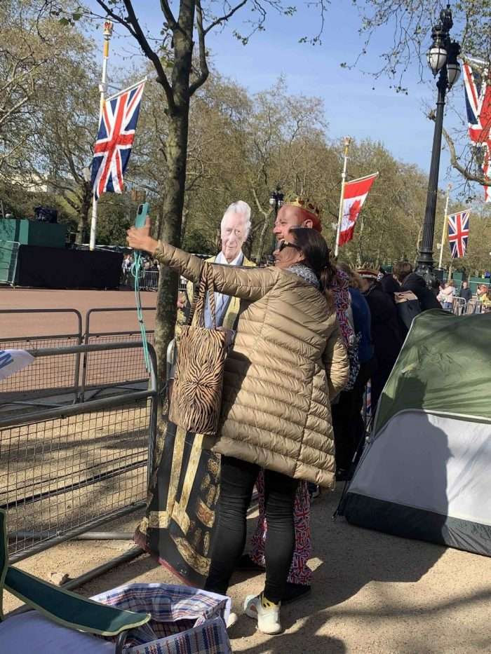 Homem com coroa e totem com a imagem do rei Charles III no cortejo da coroação