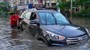 Homem empurra carro em enchente em Bangladesh, exemplo de efeito da mudança climática