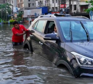 Homem empurra carro em enchente em Bangladesh, exemplo de efeito da mudança climática