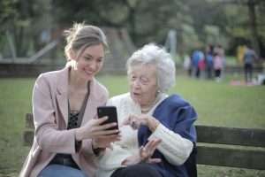 mulher jovem e idosa usando celular na praça.