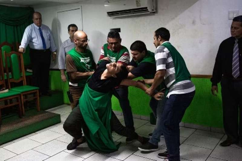 Foto de pessoas durante um culto segurando uma mulher é uma das imagens finalistas do prêmio de fotografia ética World Report Award