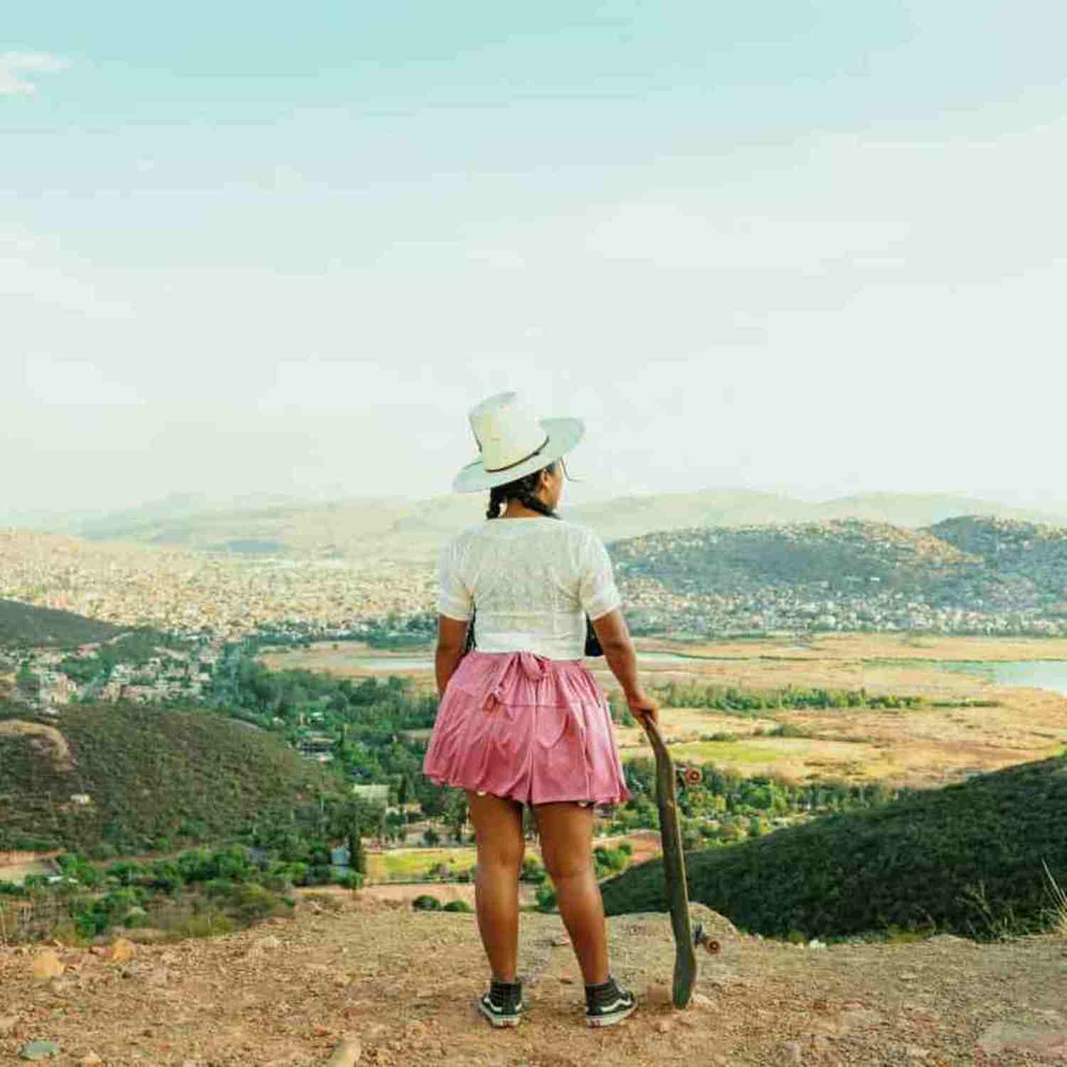 Menina vestida em roupas tradicionais segurando skate na Bolívia