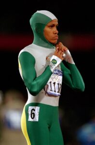 Velocista Cathy Freeman com traje de peça única da Nike nas cores verde e branca – Austrália 