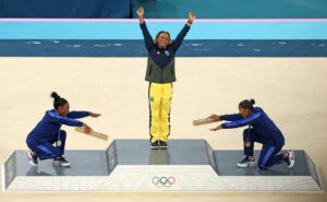 Ginasta Rebeca Andrade (medalha de ouro) é reverenciada pelas ginastas americanas Simone Biles e Jordan Chiles no pódio das Olimpíadas de Paris. Foto da Getty Images selecionada para o Dia Mundial da Fotografia