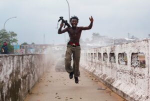 Comandante da milícia liberiana segurando arma comemora em uma ponte na Libéria. A foto foi selecionada pela Getty Images para o Dia Mundial da Fotografia