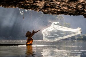 Pescador em Mianmar jogando a rede para pescar. A imagem foi uma das vencedoras do prêmio de fotos oceânicas