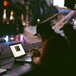 Homem em café com smartphone e notebook acessando a internet, que tem a liberdade ameaçada em vários países