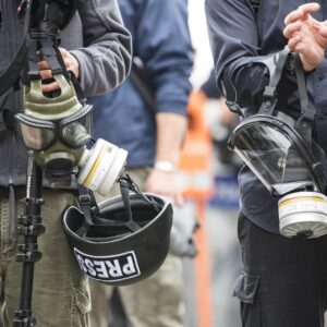 Jornalistas seguram máscaras de gás e capacetes, acessórios necessários na cobertura da guerra em Gaza