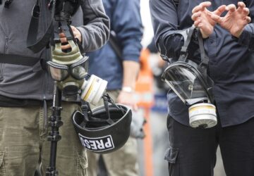 Jornalistas seguram máscaras de gás e capacetes, acessórios necessários na cobertura da guerra em Gaza