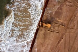 A foto mostra as obras de recuperação da orla maritíma que acontecem em Matinhos, no litoral do Paraná, Brasil. A imagem foi finalistas no concurso de fotos do meio ambiente