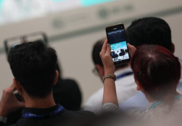 Pessoas filmando COP28 com telefone celular