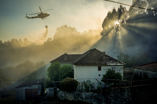 Helicóptero sobrevoa e joga água em área incendiada na Espanha. A foto foi uma das finalistas do prêmio de fotos sobre o meio ambiente