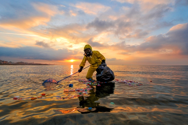 Mulher recolhe plásticos no mar na Itália. A imagem foi premiada no concurso de fotos de meio ambiente
