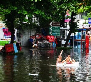 Pessoas em um barco improvisado no meio de um local inundado devido as mudanças climáticas