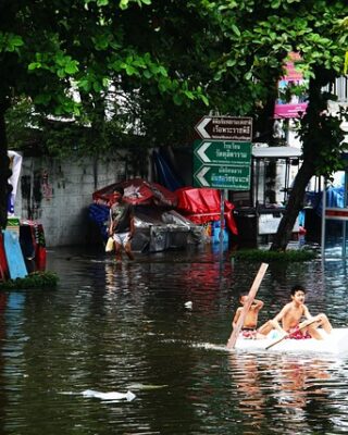 Pessoas em um barco improvisado no meio de um local inundado devido as mudanças climáticas