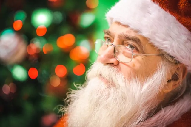 Papai Noel pensativo com árvore de Natal ao fundo