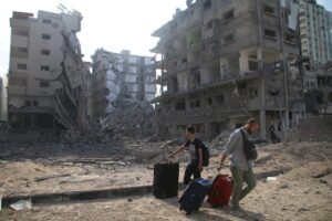 A imagem mostra cidadãos palestinos deixando suas casas danificadas pelos ataques aéreos israelenses.