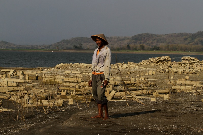Pescador perto de reservatório. A seca aumenta na Indonésia por causa do El Niño