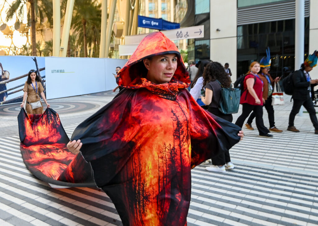 Manifestante protesta em Dubai por financiamento para afetados pela crise do clima