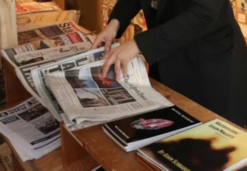 Mulher lendo jornal em banca, um hábito que vai declinando devido à crise do jornalismo