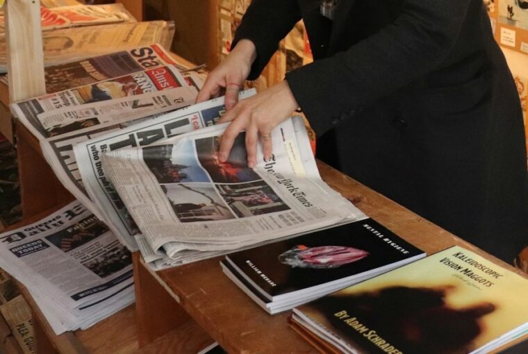 Mulher lendo jornal em banca, um hábito que vai declinando devido à crise do jornalismo