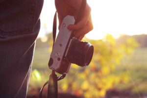 Fotógrafo segura câmera sob luz do sol na natureza