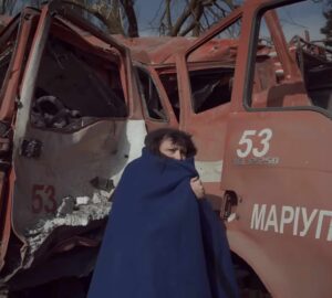Mulher diante de ambulância bombardeada em Mariupol, cena de documentário indicado ao Oscar