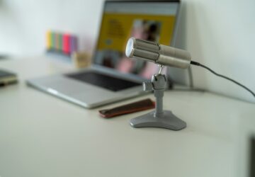 Computador e microfone sobre mesa