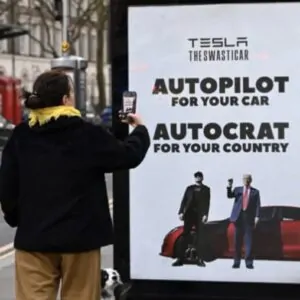 Mulher fotografa cartaz de protesto contra Elon Musk em Londres