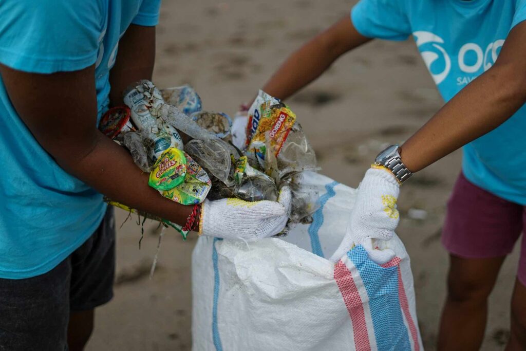 homens recolhem lixo na praia, uma das soluções para o problema de resíduos sólidos