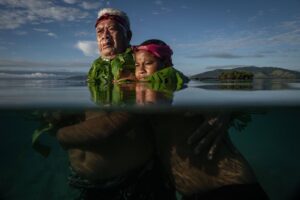 Homem com neto na água nas Ilhas Fiji, foto premiada no World Press Photo