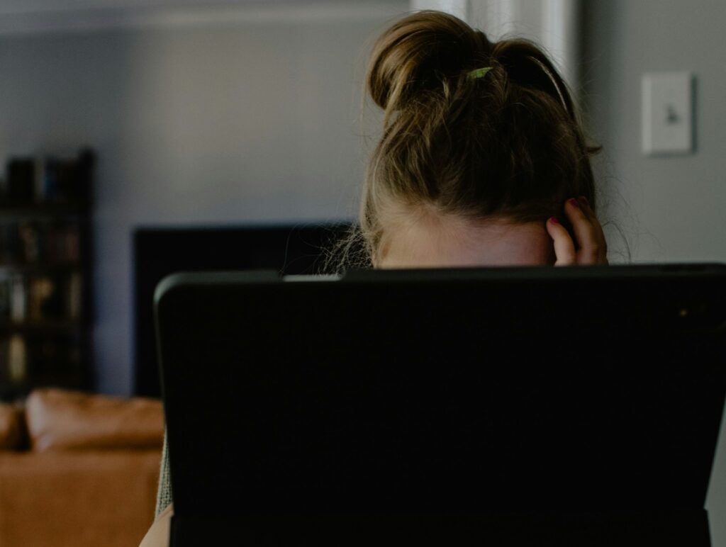 Menina olhando tela do computador, que virou porta de entrada para o abuso online