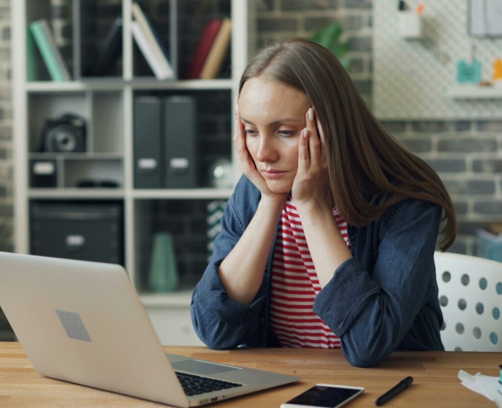 Mulher olha triste para o laptop